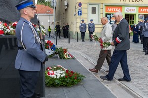 Uczestnicy uroczystości składają kwiaty pod pomnikiem