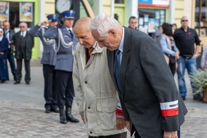 dwóch mężczyzn kłania się w stronę pomnika