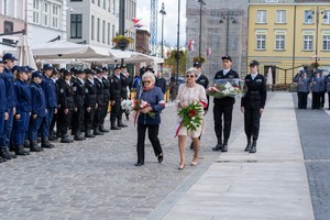 Uczestnicy uroczystości składają kwiaty pod pomnikiem