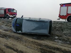 Przewrócone auto i samochody strażackie