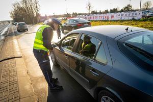 policjant kontroluje zatrzymany samochód