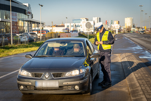 policjant kontroluje zatrzymany samochód