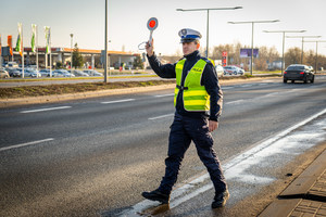 policjant podnosi rękę i zatrzymuje samochód do kontroli