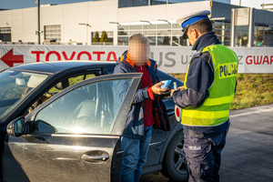 policjant kontroluje zatrzymany samochód