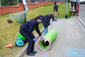 Pies przechodzi przez tunel. tunel trzyma policjantka i przewodnik