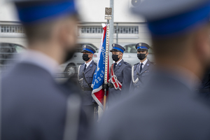 Poczet flagowy/ ujęcie zza pleców policjantów stojących w szeregu.