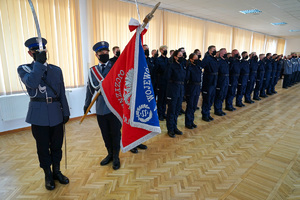 policjanci stoją w szeregu i powtarzają rotę ślubowania. A przodu stoją trzej policjanci z pocztem sztandarowym