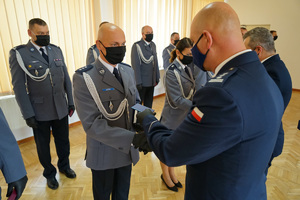 Komendant gratuluje i wręcza policjantowi legitymację do medalu