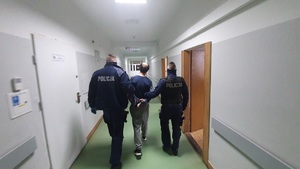 policjanci prowadzą zatrzymanego mężczyznę