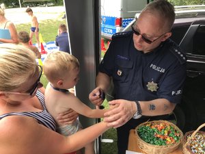 Policjant nakłada pieczątkę na rękę chłopca