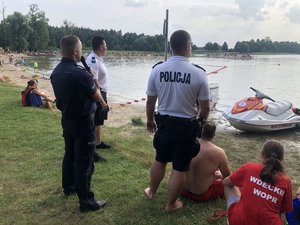 Policjanci stoją na brzegu i oglądają pokazy ratownictwa