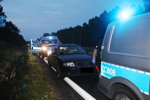 Na poboczu stoi audi za nim radiowóz z policjantem i przed nim też stoi radiowóz