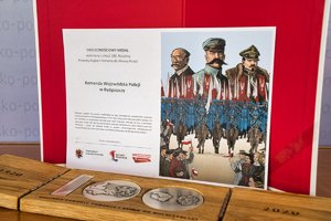 Widok na medal leżący na stole i i kartę z opisem medalu