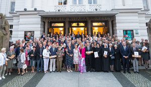 Zdjęcie grupowe, osoby stojące przed budynkiem teatru.