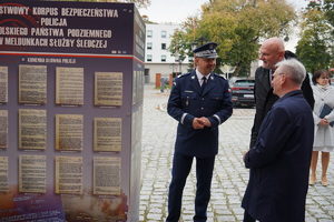 Komendant Wojewódzki Policji ogląda wystawę z Prezydentem Torunia oraz innym gościem.