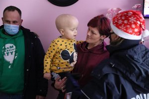 Mały chłopiec na rękach Mamy, obok policjantka i przedstawiciel fundacji