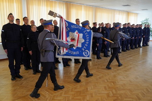 poczet sztandarowy opuszcza salę,  obok stoją policjanci ustawieni w szeregu