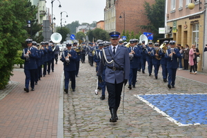 policjant prowadzi policyjną orkiestrę brukowaną drogą