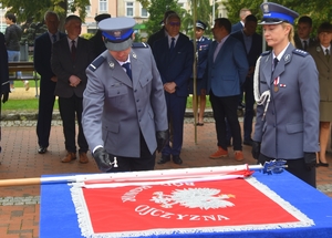 policjant przybija młoteczkiem gwóźdź do sztandaru