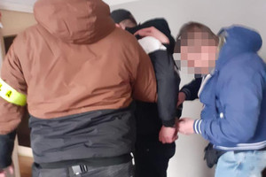 nieumundurowany policjant skuwa kajdankami ręce zatrzymanemu