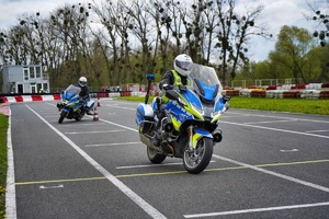 Dwóch policjantów jedzie na motocyklach po torze wyścigowym i omijają przeszkody
