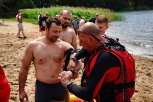 ratownik medyczny zakłada stazę na ramię mężczyzny