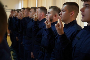 policjanci stoją w dwuszeregu z ręką uniesioną do góry