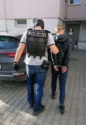 Policjant prowadzi zatrzymanego.