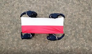 2 maja 2020 roku. Dzień Flagi Rzeczypospolitej Polskiej. Policjanci 1 kompanii Oddziału Prewencji Policji w Warszawie wciągają flagę na maszt przed Pałacem Mostowskich, siedzibą Komendy Stołecznej Policji.