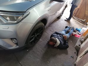Stodoła, a w niej samochód, obok którego leży zatrzymany przez policjantów mężczyzna.