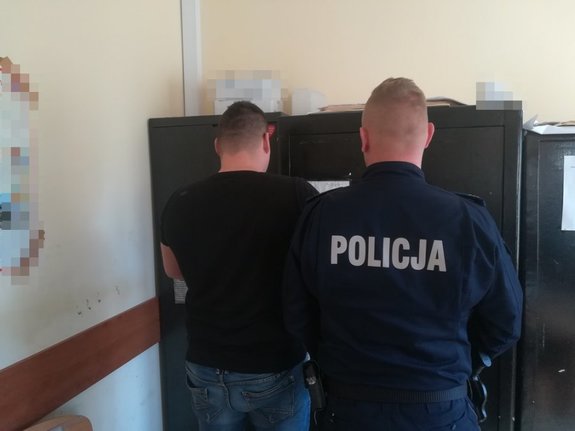 Policjant prowadzi zatrzymanego mężczyznę