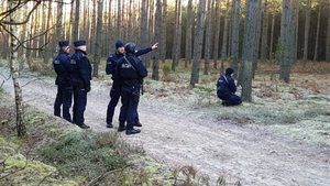policjanci stoją na leśnej drodze.