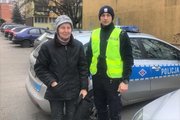 policjant ruchu drogowego stoi wraz ze starszą panią na tle radiowozu