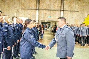 Zastępca Komendanta Wojewódzkiego Policji w Łodzi składa gratulacje policjantom podczas ślubowani, w tle kadra kierownicza łódzkiej policji.