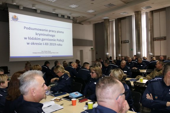 Widok na siedzących na sali policjantów oraz slajd prezentacji.