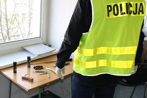 Policjant zabezpiecza niebezpieczne narzędzia znalezione u zatrzymanego.