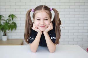 Dziewczynka z rękoma opartymi o stół.