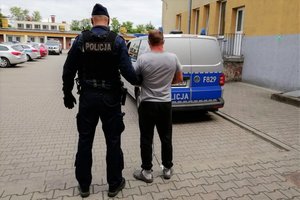 Policjant prowadzi zatrzymanego.