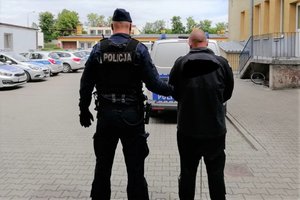 Policjant prowadzi zatrzymanego.