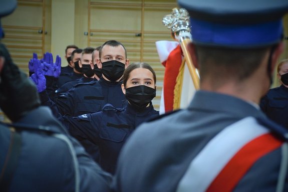 Sala gimnastyczna Oddziału Prewencji Policji w Łodzi, uroczystość ślubowania policjantów, poczet sztandarowy, policjanci recytują rotę ślubowania.