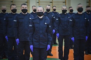 Sala gimnastyczna Oddziału Prewencji Policji w Łodzi, uroczystość ślubowania policjantów, policjanci stoją w kolumnie czwórkowej.