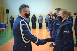 Sala gimnastyczna Oddziału Prewencji Policji w Łodzi, uroczystość ślubowania policjantów, komendant wojewódzki wręcza policjantce legitymację służbową.