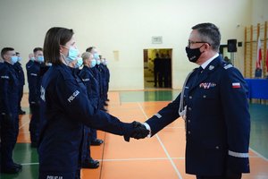 Sala gimnastyczna oddziału prewencji policji w Łodzi, uroczystość ślubowania, komendant uściskiem dłoni wita w szeregach policji nową funkcjonariuszkę.