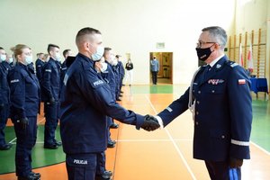 Sala gimnastyczna Oddziału Prewencji Policji  w Łodzi. uroczystość ślubowania policjantów. Komendant ściska dłoń nowo przyjętemu policjantowi.