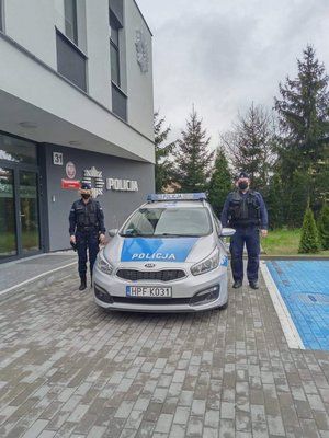 Radiowóz w tle komenda, a obok policjanci.