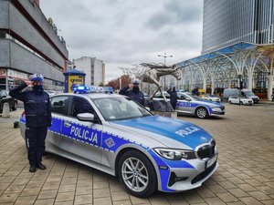 Oznakowany radiowo obok oddający honor policjanci.