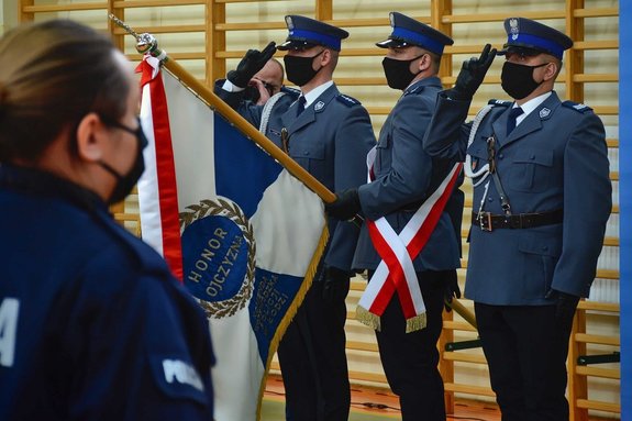 Policjantka stojąca przed pocztem sztandarowym.