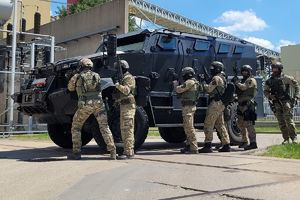 Policjanci stoją za pojazdem policyjnym.