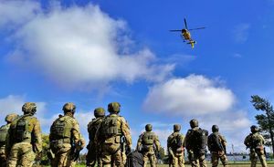 Policjanci patrzą na lecący helikopter.