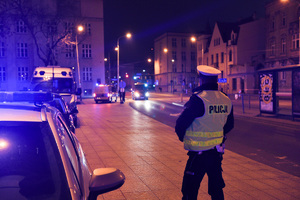 Policjant przy radiowozach.